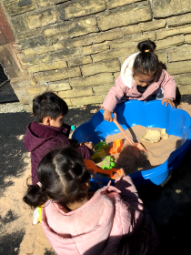 Children playing in a sandpit in the sun.