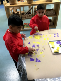 Children playing with purple and yellow shapes at a table.