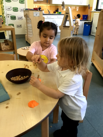 Children at a desk with a bowl of small stones.