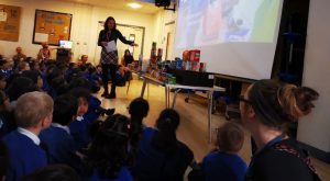 A teacher talking at the front of assembly.