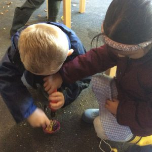 Two children working on the floor in forest school.